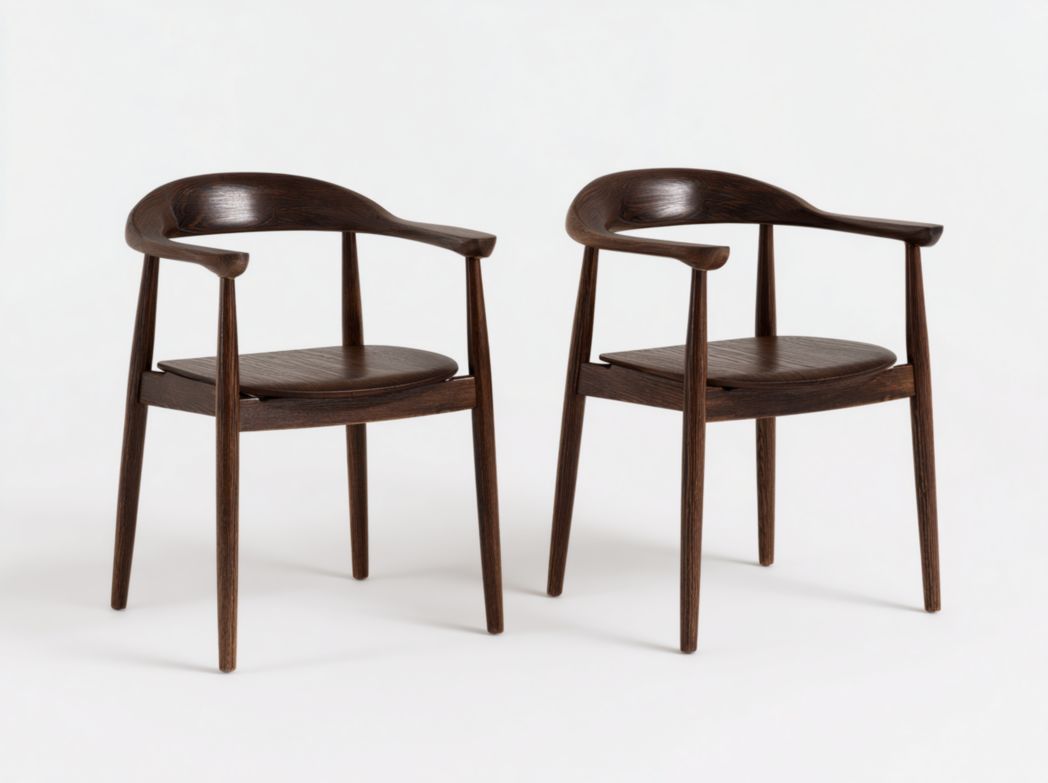 Deux chaises de salle à manger en bois foncé avec dossiers et accoudoirs incurvés