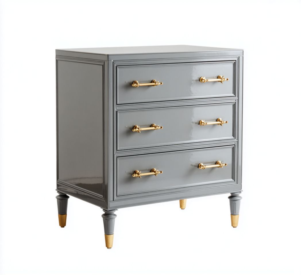 Commode grise en bois à trois tiroirs avec poignées dorées et pieds ornés