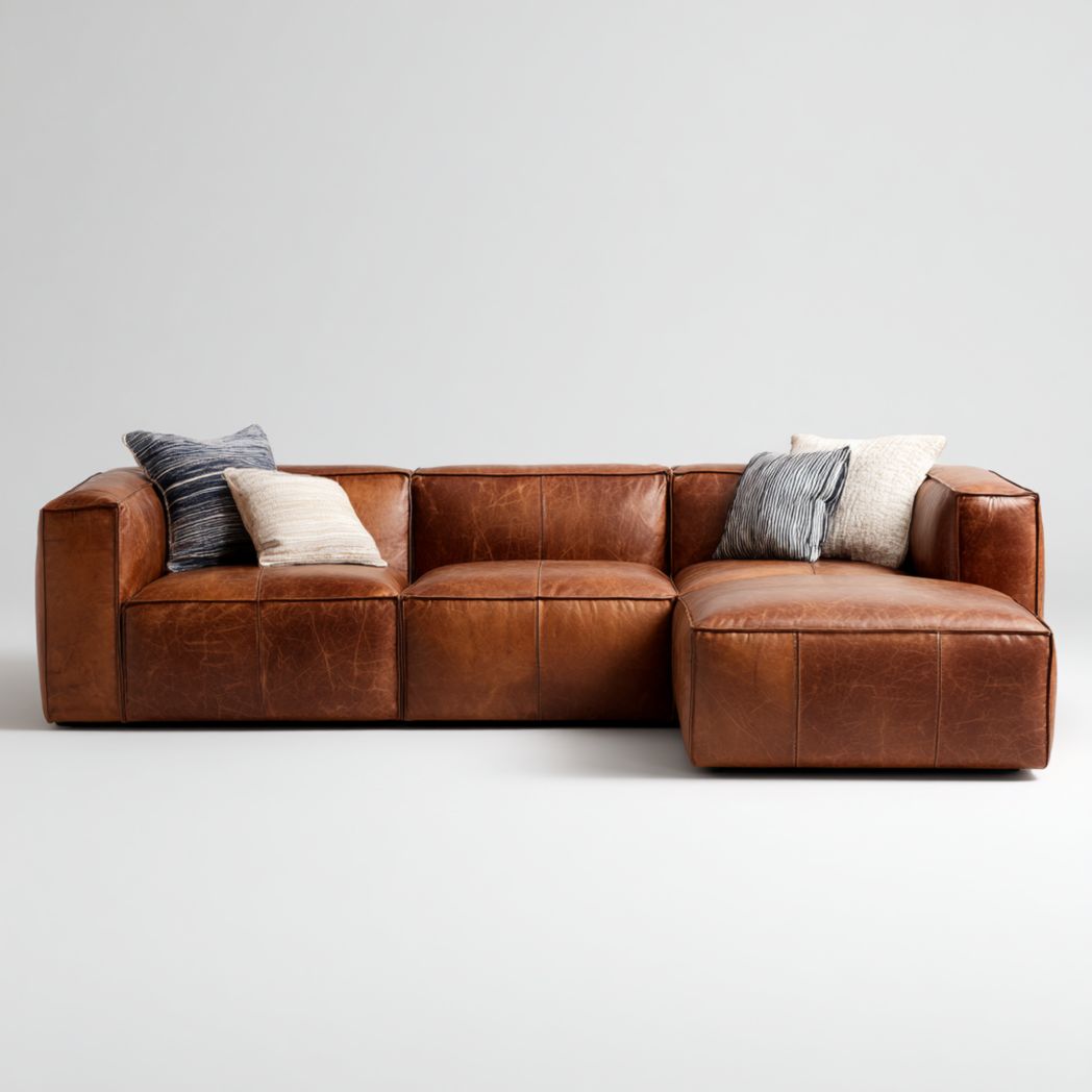 Canapé d'angle en cuir marron avec un design modulaire en forme de L et quatre coussins en tissu.